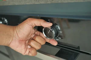 Technician installing refrigerator thermostat control dial with precision tools