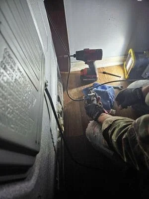 Technician repairing refrigerator compressor with power tools and diagnostic equipment