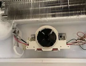Evaporator fan motor assembly with black fan blade and white housing, electrical wiring connections visible