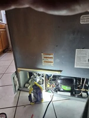 Open commercial refrigeration unit showing compressor, wiring, and internal mechanical components during service